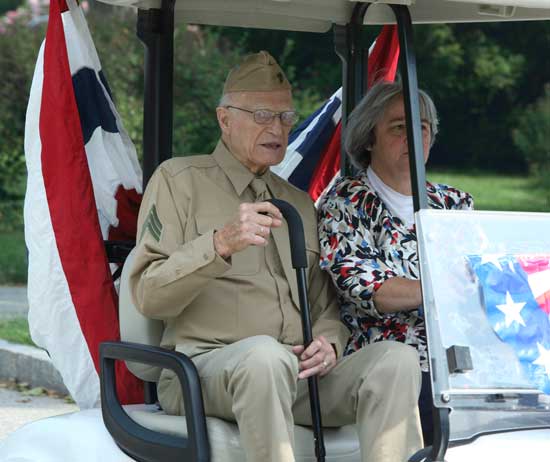 World War II veteran Bill Doe rides in style in a golf cart driven by Vietnam veteran Nancy Cronin