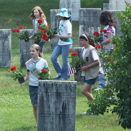 Girl Scouts fan out across the town center cemetery on Memorial Day, May 31, delivering geraniums to decorate the graves of veterans.