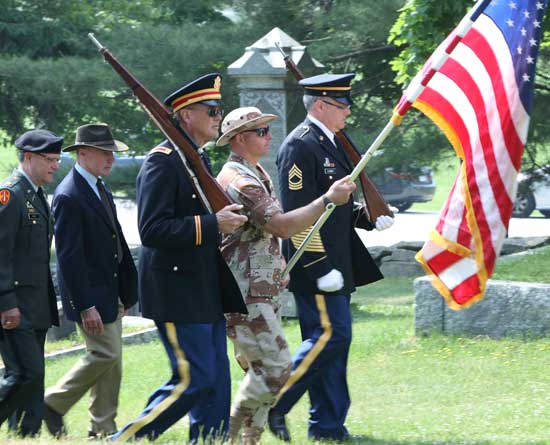 The color guard leads the parade through the town center cemetery.