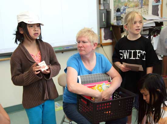 Daisy Benson (left) shows off a mini-book she made as For Art’s Sake project creator and  leader Bess Haire and Kiersten Niland look on.