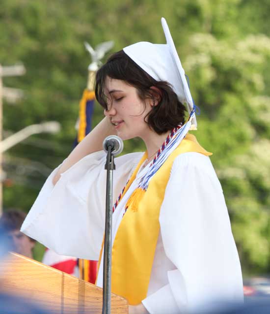 Valedictorian Dominique Ledoux delivers her speech while trying to hold on to her hat in the wind.