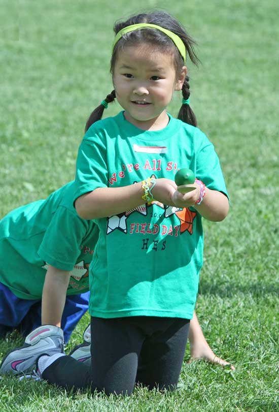 Kindergartener Olivia Ren balances an egg on a spoon in preparation for a race.