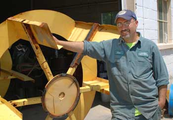 DPW mechanic Geno Vazquez stands beside the old paddlewheels taken off the weed harvester. (Photo by Sue Fitterman)