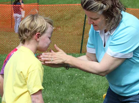 Aidan von Conta gets slathered with sunscreen by his mom, Sarah Connolly