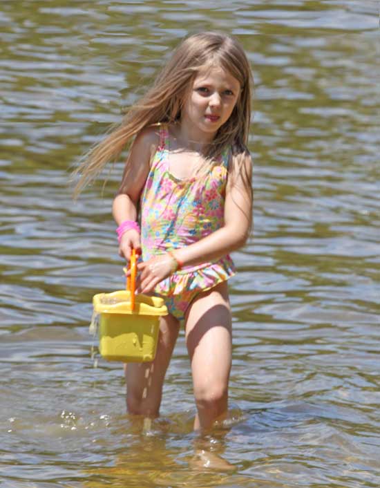 Faith Massoni wets a bucket of sand for building a sandcastle.