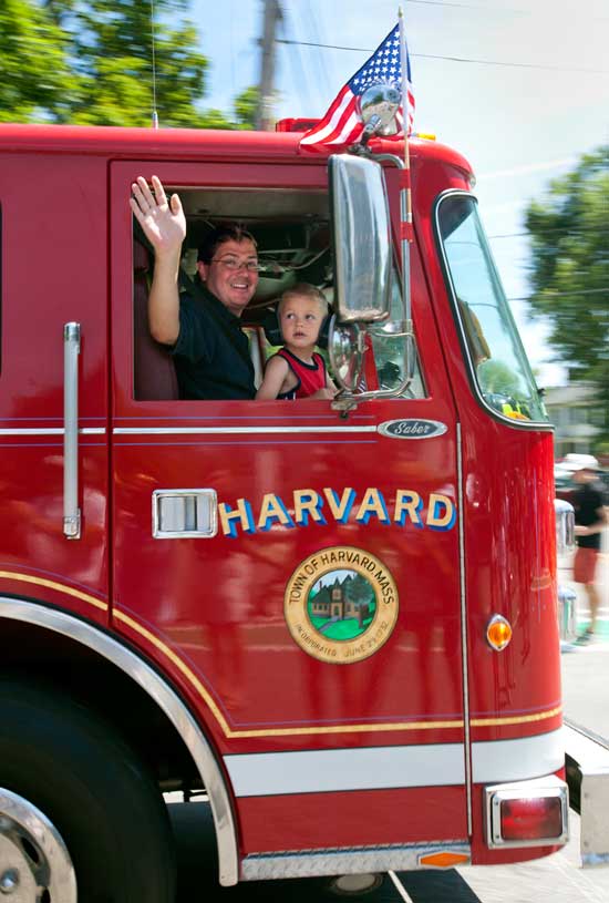 A Harvard fire truck goes by as a firefighter waves a friendly greeting. (Photo by Ellen Harsimowicz)