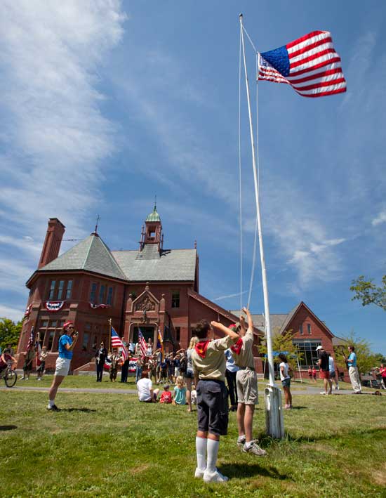 A Boy Scout salutes as another raises the flag. (Photo by Ellen Harasimowicz)
