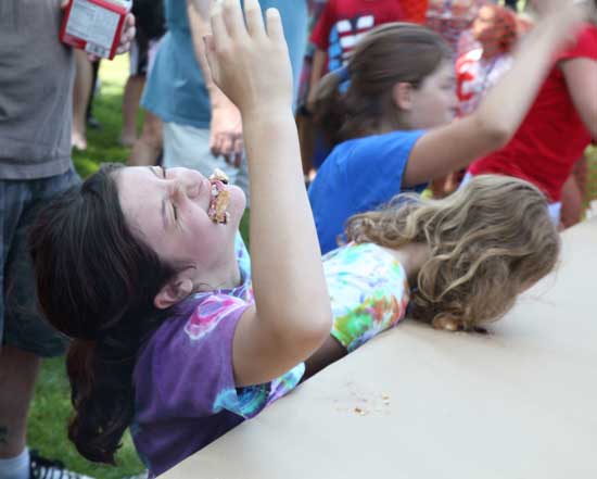 Carlisle Ferguson holds up her hand in victory, winning her division in the pie-eating contest, as her mouth overflows with pie.