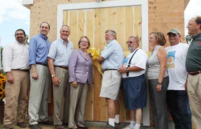 From left: Commissioner of the Mass. Department of Agriculture Scott Soares, State Senator Jamie Eldridge, Director of Rural Development for the U.S. Department of Agriculture Jay Healey, U.S. Representative Niki Tsongas, Frank Carlson, Robert Carlson, President of EC3 Consulting Samantha Gates, Bruce Carlson, and David Weiher prepare to cut the ribbon and throw the switch on the solar panel array. (Photo by Lisa Aciukewicz)