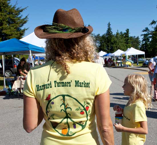One of the Harvard Farmers’ Market organizers, Jennifer Sundeen, seen here with daughter Kellie, displays the winning T-shirt design by Bromfield graduate and college art student Ellery Yahia.