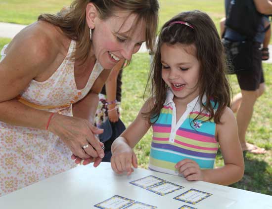 Becky Moran (left) helps her daughter Abigale look for her name tag at the kindergarten picnic on Aug. 31.