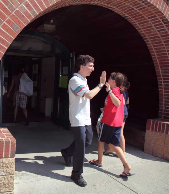 HES music teach David Gilfix greets studens with a high-five at the entrance to the school.