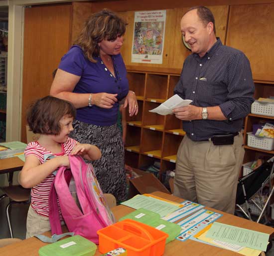 First-grader Rachel Graham upacks her school supplies as teacher Lisa Hopkins and Rachel’s father, Don Graham, go over details at the Open House.