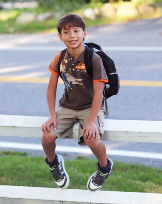 First-grader Geraghty Vellante waits on a fence for the bus on Still River Road.