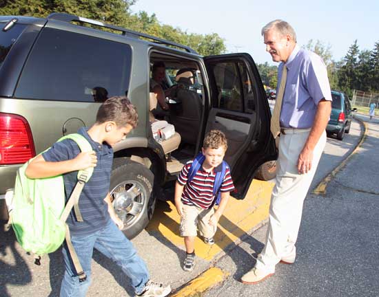 School Superintendent Thomas Jefferson greets the Carbonell brothers, third-grader Charlie (left) and first-grader Benjamin, as they are dropped off at HES.