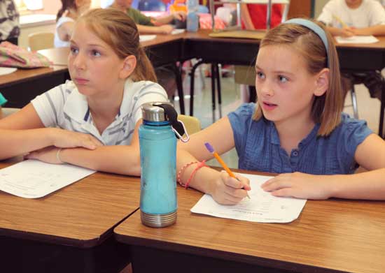 Fifth-graders Catherine Caruso and Sofia MacLean listen to their teacher, Joan Accorsi.