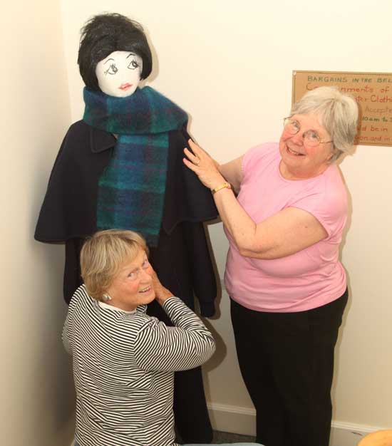 Teddy Coffin (left) and Diane Cordner attire Molly the mannequin on the stairway to Bargains in the Belfry, the resale shop operated by the Women's Alliance of the Harvard Unitarian Church.
