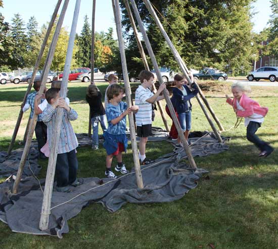 Charlotte Dewitt (far right) swings on a rope to tightly tie the top of a teepee constructed by her classmates from Mrs. Ames' second-grade class. The teepee construction was part of the HES curriculum on Native Americans.