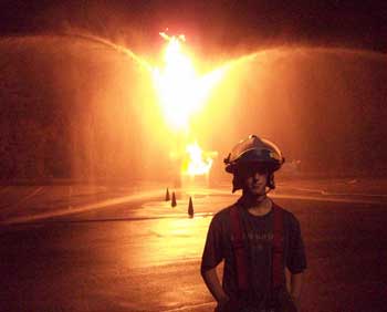 A firefighter sprays water at a liquid propane fire simulating a blown flange between two pipes. The training was part of a gas fire course held at the Massachusetts Fire Academy in Stow that Harvard firefighters attended in October 2008.(Courtesy photo by Bob Mignard)