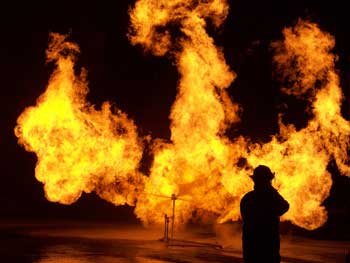 A firefighter sprays water at a liquid propane fire simulating a blown flange between two pipes. The training was part of a gas fire course held at the Massachusetts Fire Academy in Stow that Harvard firefighters attended in October 2008.(Courtesy photo by Bob Mignard)