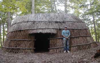 Artist Jeff Kalin poses in front of a longhouse he built that is similar to the one being built at Fruitlands.(Courtesy photo)