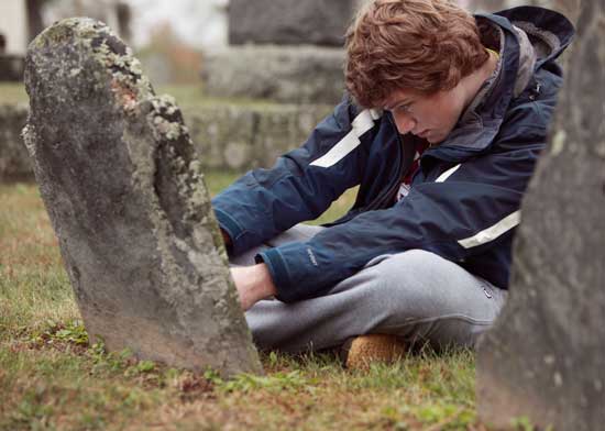 Harvard University student Ian Shields takes a measurement of some of the lichens on a headstone in the Town Center Cemetery.