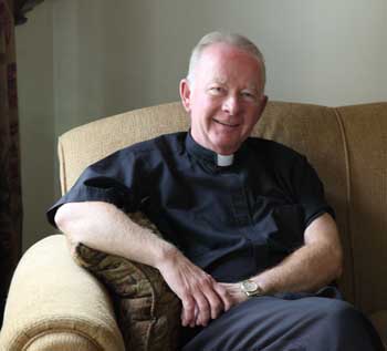 Rev. Terence T. Kilcoyne relaxes in the rectory at Holy Trinity Parish in Harvard. (Photo by Lisa Aciukewicz)