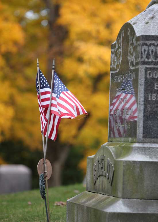 American flags reflect off the grave of veterans at Bellevue cemetery.