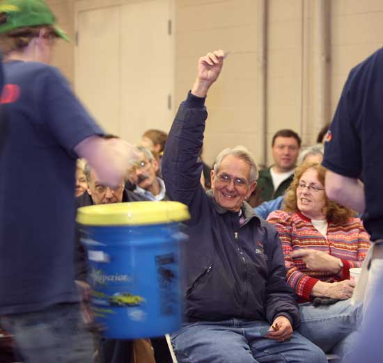 Jerry Copeland, former Harvard postmaster, holds up his winning ticket as his wife Judy looks on. Copeland won a car care kit.