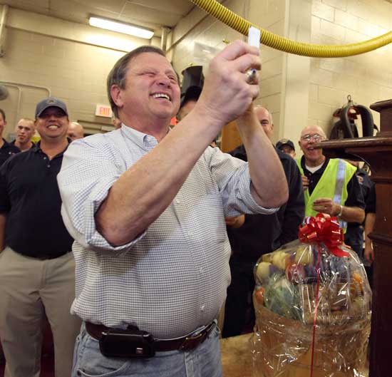 Selectman Ron Ricci uses a magnifier to verify the number on his winning ticket as Tony Shaw, the emcee, looks on. Ricci was dumbstruck to discover he had drawn his own number when asked to pull the winning ticket for the much- anticipated flat-screen TV.