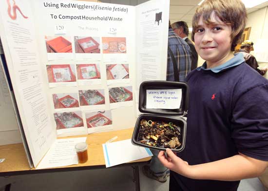 Daniel Shrives holds up a container of compost being devoured by red worms.