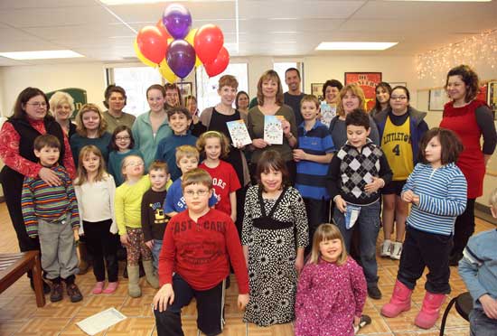 Authors Donna Shea and Nadine Briggs (center) display copies of their book. They are surrounded by children and parents at the Peter Pan Center on Ayer Road. (Photo by Lisa Aciukewicz)