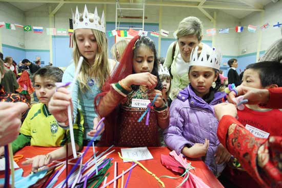 A swarm of students gathers around a table, making Japanese flowers out of pipe cleaners.