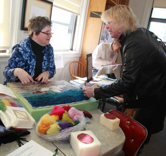 Felting artist Lyn Slade (left) discusses one of her felt “paintings” with Ellen Cavanagh