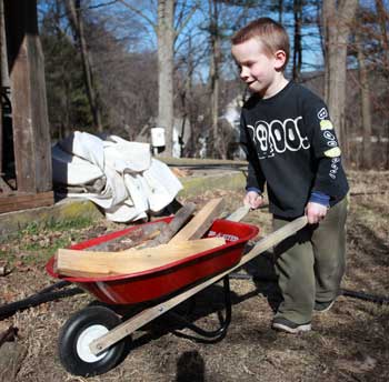 Pushing a mini wheelbarrow of wood, Jim’s five-year-old son, Harry, has been helping out since he was two. (Photo by Lisa Aciukewicz)
