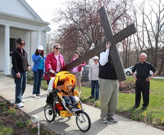 The McFarland family prepares to set off from Holy Trinity Parish in Harvard to the Bolton site with a wooden cross on a symbolic Good Friday walk with members of both congregations. At right is Father Terence Kilcoyne.