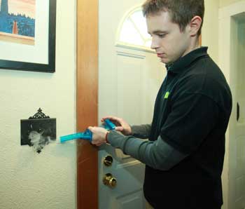 Jonathan Farrell of Next Step Living uses a “wizard stick” to check the potential heat loss from a switchplate. (Photo by Lisa Aciukewicz)