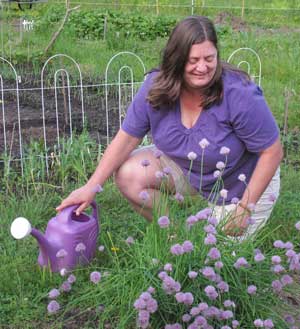 Carolena McCauly waters chives at the community garden. (Photo by Lisa Aciukewicz) Carolena McCauly waters chives at the community garden. (Photo by Lisa Aciukewicz)
