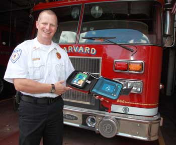 New Fire Chief Rick Sicard holds up an automated external defibrillator (AED). He hopes to equip all town fire engines with them. (Photo by Lisa Aciukewicz) New Fire Chief Rick Sicard holds up an automated external defibrillator (AED). He hopes to equip all town fire engines with them. (Photo by Lisa Aciukewicz)