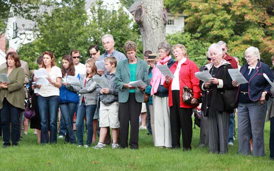 Those gathered at the memorial on the common sing "Let There Be Peace on Earth."