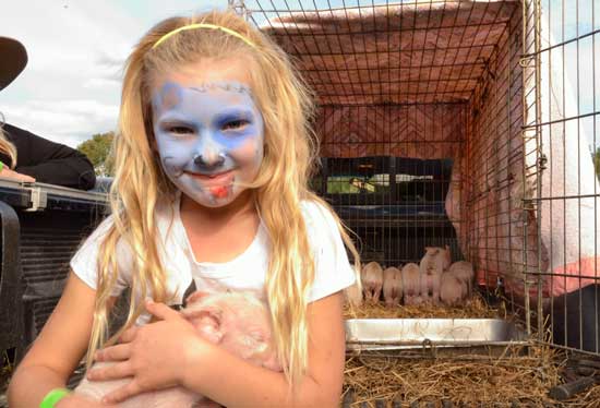 Maria Anderson of Still River Farm holds a two-week-old piglet. (Photo by Katy Sharko)