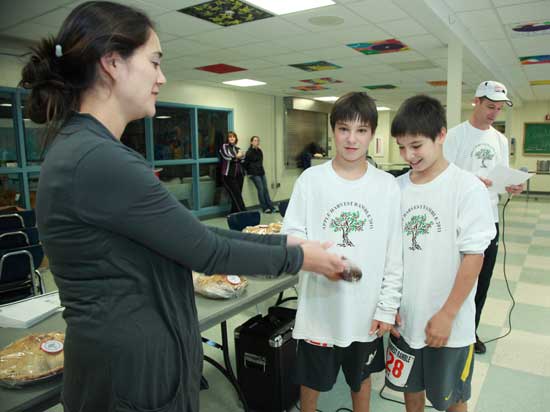 Anne Stahl presents her nephews Matthew and Michael Thornton with some honey for their second-place tie in the 1-19 age group as father Mike looks over the results. 