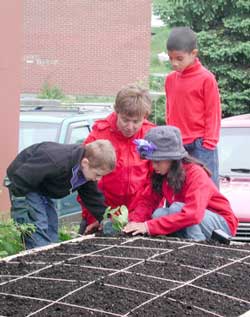 Kate Deyst (center) helps a group of children plant a garden during a Growing Places Garden Project installation. (Courtesy photo) Kate Deyst (center) helps a group of children plant a garden during a Growing Places Garden Project installation. (Courtesy photo)
