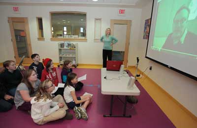Sixth-Grade Book Club members speak via web-cam with author M. T. Anderson at the library on Dec. 20 as librarian Abby Kingsbury looks on. (Photo by Lisa Aciukewicz)