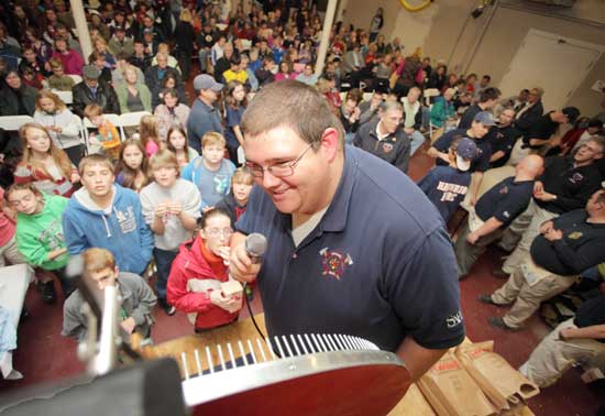 Firefighter Andrew Perry reads a winning number off the wheel to an expectant audience at the Fire Department's annual Turkey Raffle.
