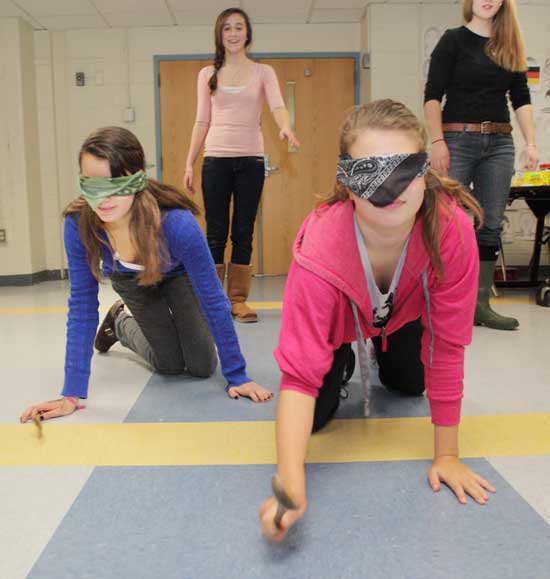 Blindfolded Alexis Norcross (left) and Ali Goldsher play a German game at the Ludo Festival, Jan. 12 at the Bromfield School.
