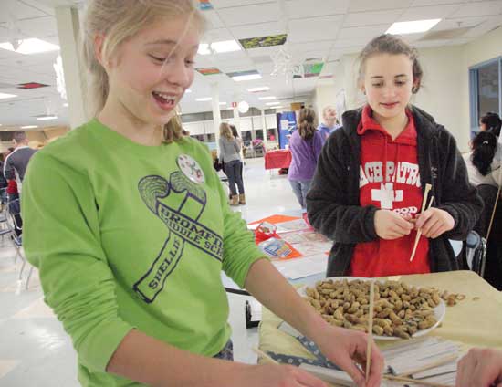 Lily Moore-Eisenberg and Kelsey L’Ecuyer try their hands at using chopsticks to pick up peanuts.