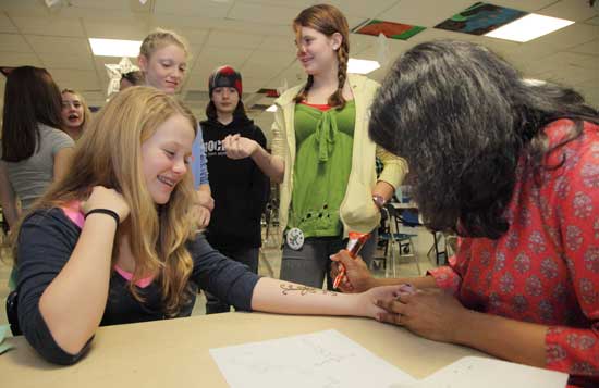 Devika Kommineni (right) adorns Maeve French's arm with henna.