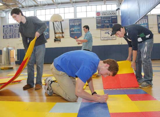 Ian Harrington, Drew Banker, and Bin Han snap floor tiles together to form the evening’s dance floor.