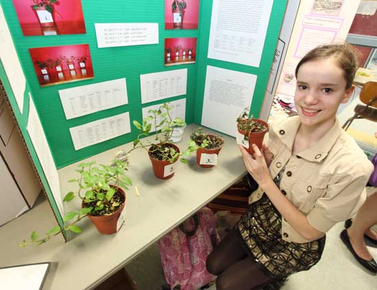 Hannah Kline holds up a plant on which she tested the effects of pH levels on coloration and growth. She won an award from the Conservation Trust.